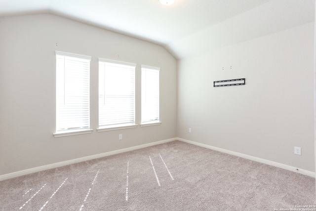 empty room with vaulted ceiling, light carpet, and plenty of natural light