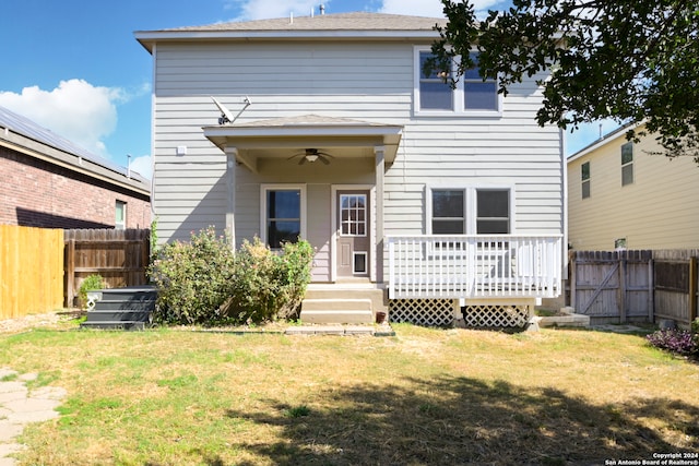 back of house with ceiling fan, a deck, and a lawn