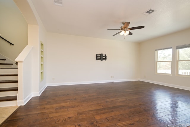 spare room with ceiling fan, built in features, and dark hardwood / wood-style flooring