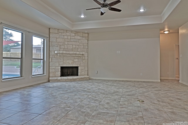 unfurnished living room with light tile patterned floors, ceiling fan, a tray ceiling, ornamental molding, and a fireplace