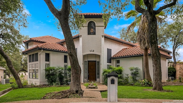 mediterranean / spanish-style home featuring a front yard and cooling unit