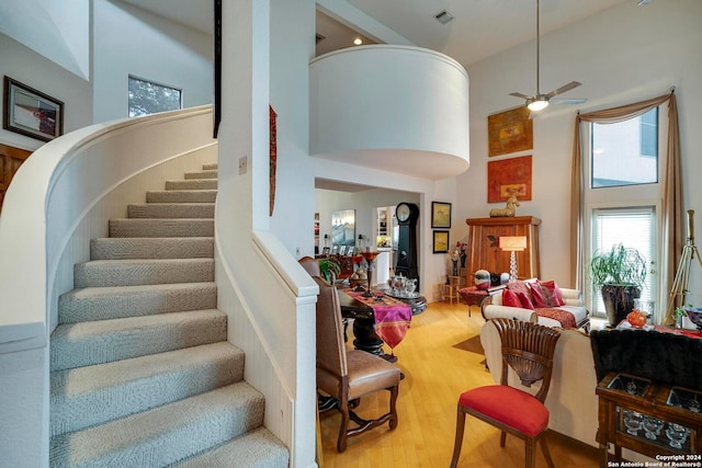 living room featuring wood-type flooring, a high ceiling, and ceiling fan