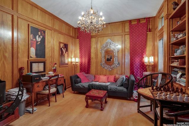 sitting room with light hardwood / wood-style flooring, ornamental molding, wooden walls, and a notable chandelier