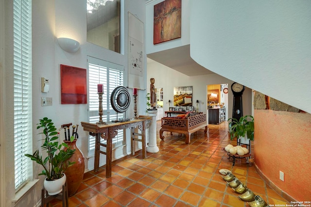 hall featuring a towering ceiling and tile patterned flooring