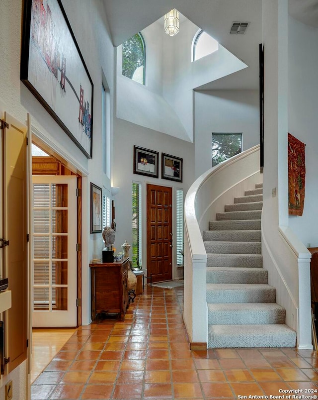 entrance foyer with light tile patterned flooring, a towering ceiling, and plenty of natural light