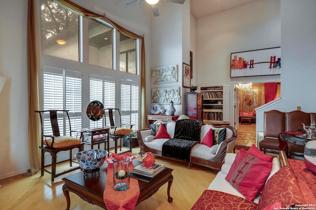 living room featuring a high ceiling, light wood-type flooring, and ceiling fan