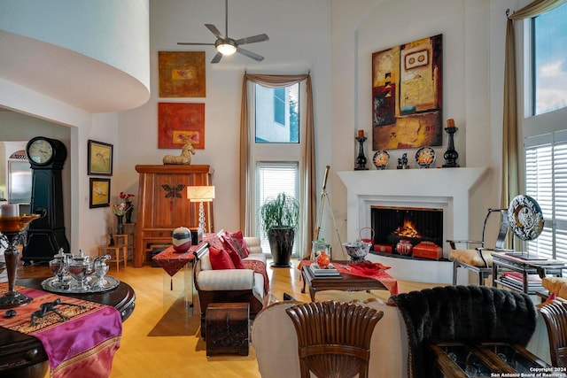 sitting room featuring a towering ceiling, light wood-type flooring, and a wealth of natural light