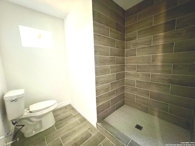 bathroom featuring a tile shower and toilet