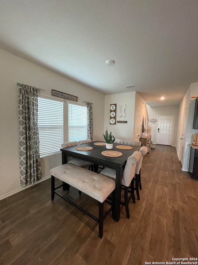 dining room featuring dark wood-type flooring and a textured ceiling