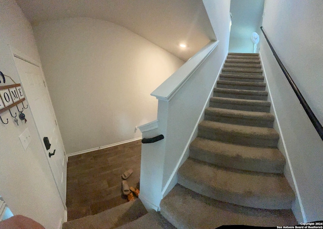 stairway featuring lofted ceiling and hardwood / wood-style floors