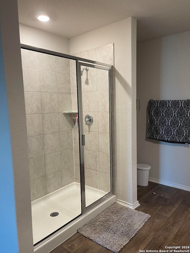 bathroom featuring toilet, an enclosed shower, and hardwood / wood-style floors