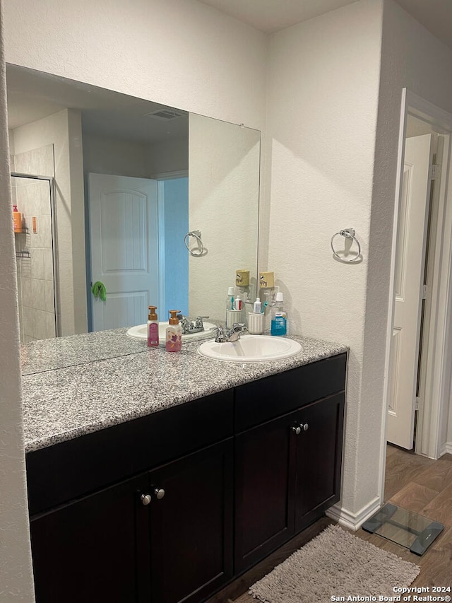 bathroom featuring vanity, an enclosed shower, and wood-type flooring