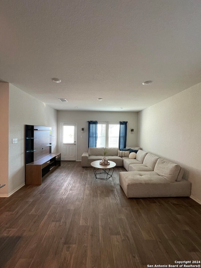 unfurnished living room featuring a textured ceiling and dark hardwood / wood-style flooring