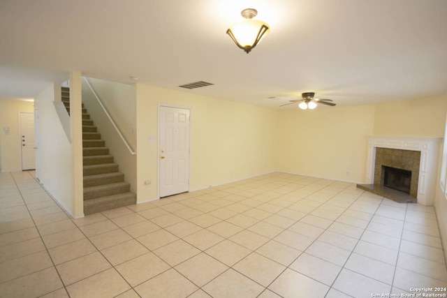 unfurnished living room featuring ceiling fan, a tile fireplace, and light tile patterned floors