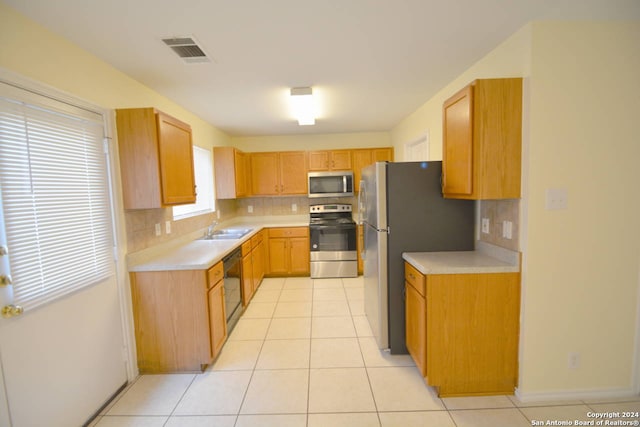 kitchen with light tile patterned floors, stainless steel appliances, decorative backsplash, and sink