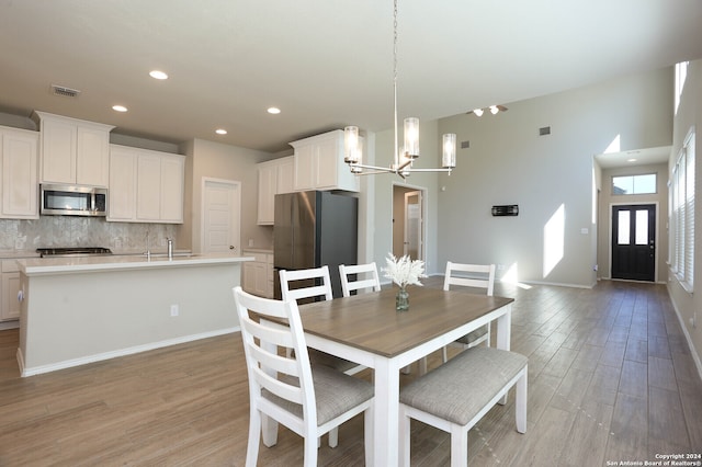 dining space featuring sink, a chandelier, and light wood-type flooring