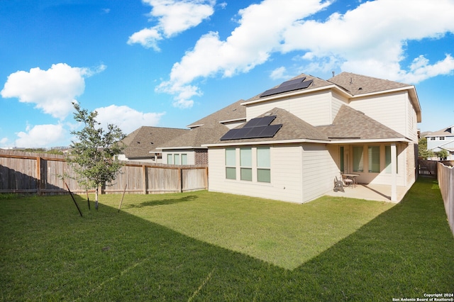 back of house featuring a patio, a yard, and solar panels