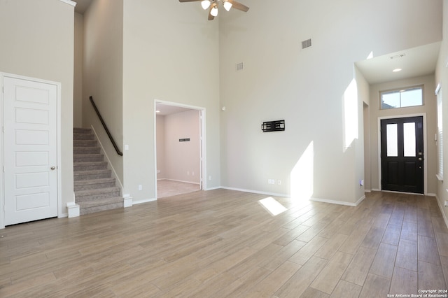 foyer with light hardwood / wood-style flooring, a high ceiling, and ceiling fan