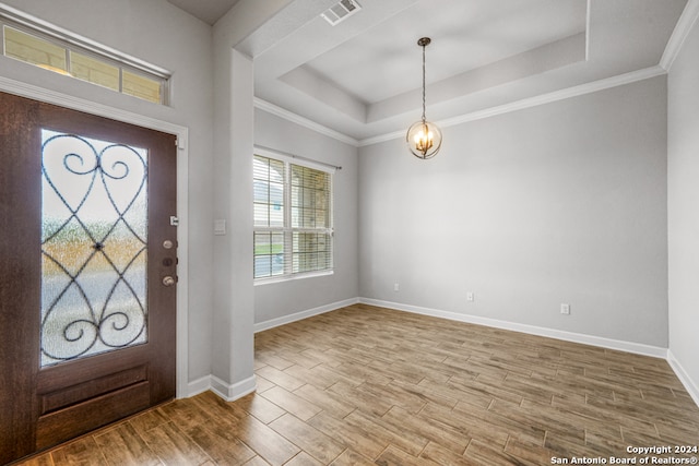 foyer with ornamental molding, a notable chandelier, hardwood / wood-style flooring, and a tray ceiling