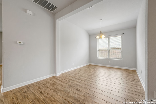 unfurnished room with a notable chandelier and light hardwood / wood-style flooring