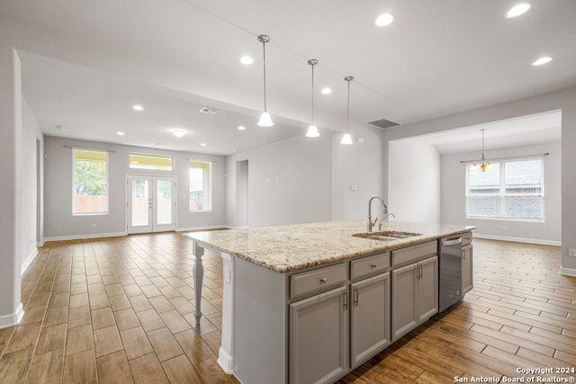 kitchen featuring a healthy amount of sunlight, a kitchen island with sink, sink, and dishwasher