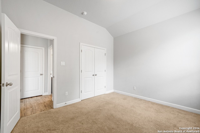 unfurnished bedroom with a closet, carpet flooring, and lofted ceiling