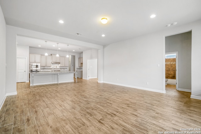 unfurnished living room with sink and light wood-type flooring