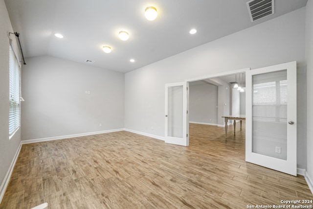 unfurnished room featuring french doors, vaulted ceiling, and light wood-type flooring