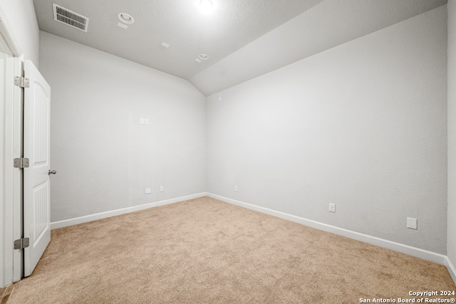 carpeted empty room featuring vaulted ceiling