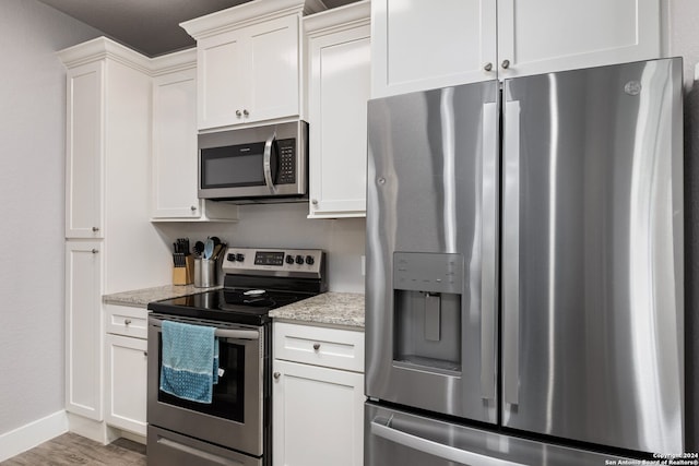 kitchen featuring light stone countertops, appliances with stainless steel finishes, hardwood / wood-style flooring, and white cabinets