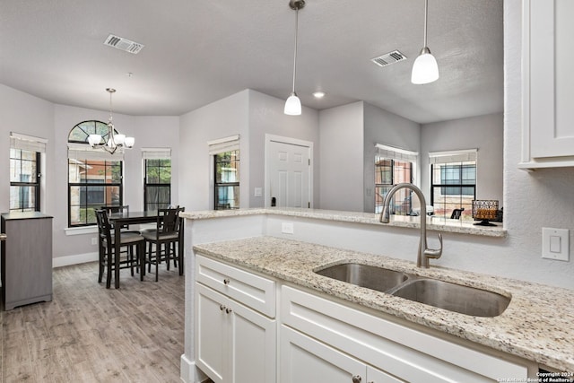 kitchen with light hardwood / wood-style floors, white cabinetry, a healthy amount of sunlight, and sink