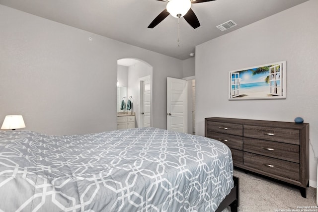 bedroom featuring connected bathroom, light colored carpet, and ceiling fan