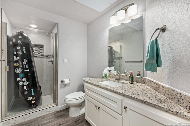 bathroom featuring a skylight, an enclosed shower, hardwood / wood-style floors, toilet, and vanity