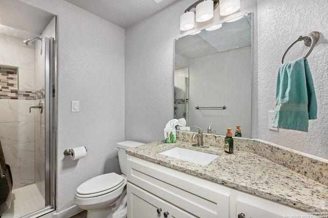 bathroom featuring vanity, toilet, and a shower with shower door