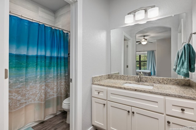 bathroom featuring toilet, hardwood / wood-style floors, ceiling fan, vanity, and walk in shower