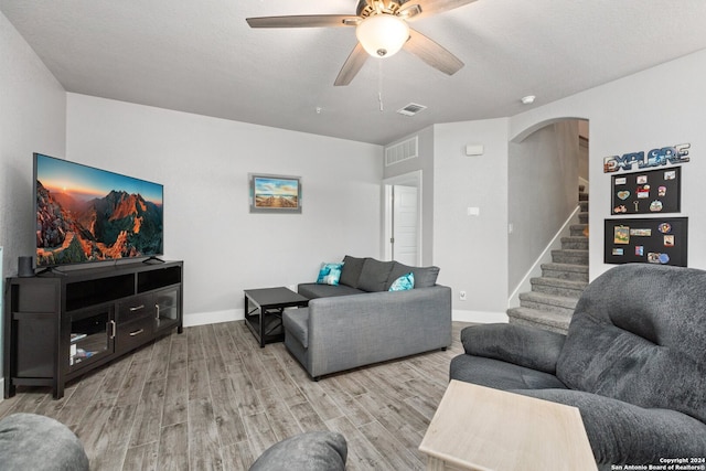 living room featuring light hardwood / wood-style flooring, a textured ceiling, and ceiling fan