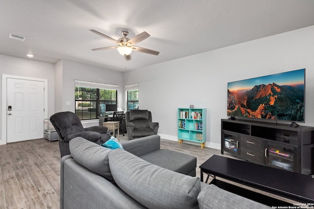 living room featuring ceiling fan, a textured ceiling, and light wood-type flooring