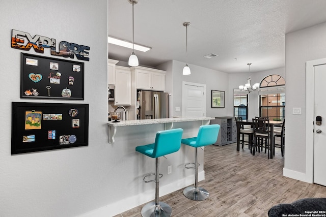 kitchen with a kitchen breakfast bar, light hardwood / wood-style flooring, kitchen peninsula, stainless steel appliances, and white cabinets