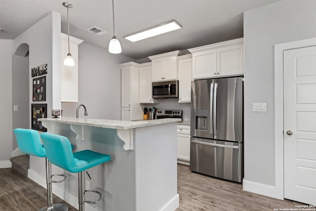 kitchen featuring white cabinetry, stainless steel appliances, light hardwood / wood-style flooring, and a breakfast bar area