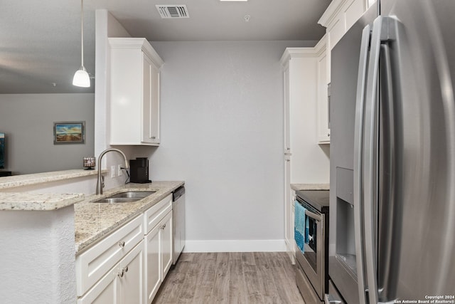 kitchen with appliances with stainless steel finishes, white cabinetry, light hardwood / wood-style flooring, pendant lighting, and sink