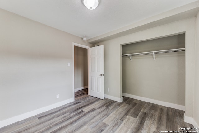 unfurnished bedroom with a closet, wood-type flooring, and a textured ceiling