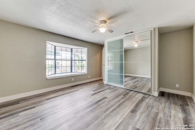 unfurnished bedroom featuring a textured ceiling, light wood-type flooring, a closet, and ceiling fan