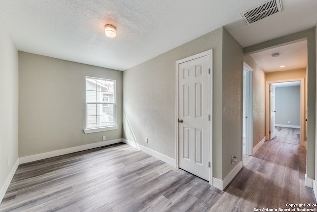 empty room with a textured ceiling and hardwood / wood-style flooring