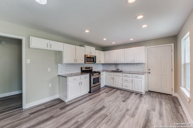 kitchen featuring white cabinets, light stone countertops, light hardwood / wood-style flooring, sink, and stainless steel appliances