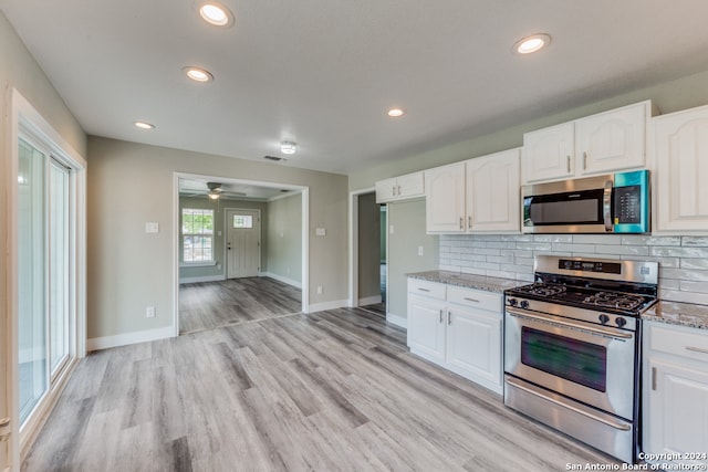 kitchen with appliances with stainless steel finishes, light stone counters, and white cabinetry