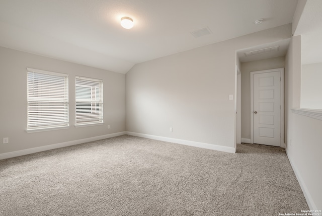 carpeted empty room with lofted ceiling