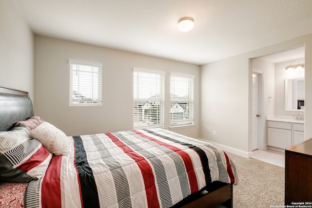 carpeted bedroom featuring sink and connected bathroom