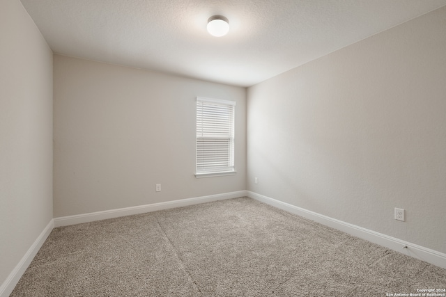 carpeted empty room featuring a textured ceiling