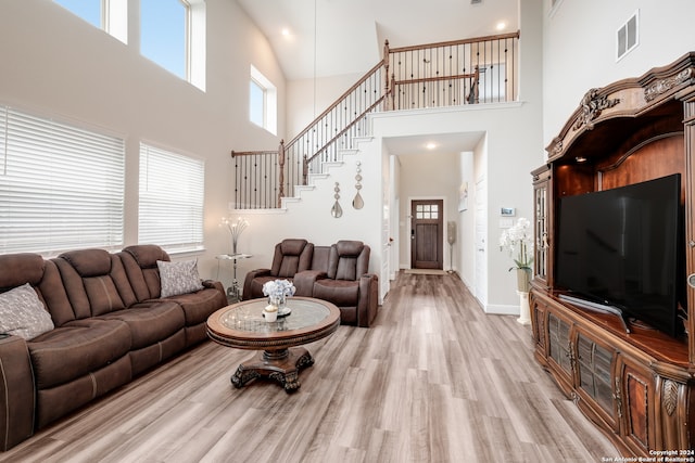 living room featuring a towering ceiling and light wood-type flooring