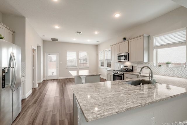 kitchen featuring sink, a kitchen island, light stone counters, and stainless steel appliances